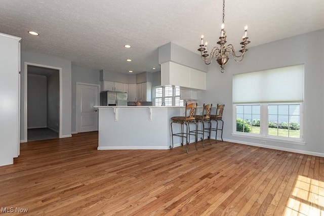 415 Cascade Ct, Avon Lake, OH 44012 - kitchen featuring freestanding refrigerator, light wood-style floors, a chandelier, a kitchen breakfast bar, and white cabinetry