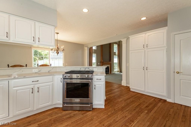 415 Cascade Ct, Avon Lake, OH 44012 - kitchen with high end stainless steel range, light wood-type flooring, a chandelier, white cabinetry, and recessed lighting