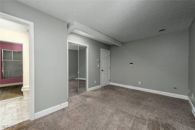 1915 Claus Rd, Vermilion, OH 44089 - unfurnished bedroom featuring a textured ceiling, a closet, carpet, connected bathroom, and a baseboard radiator