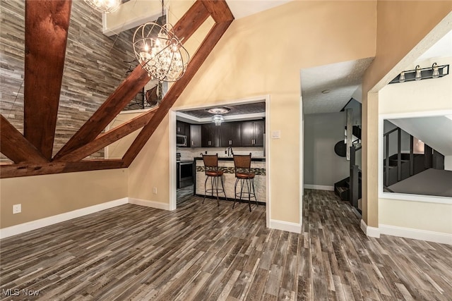 1915 Claus Rd, Vermilion, OH 44089 - unfurnished living room featuring dark wood-type flooring, a chandelier, and high vaulted ceiling