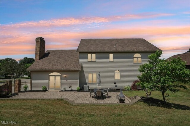 1101 Partridge Dr, Wadsworth, OH 44281 - back of house at dusk featuring a patio, a chimney, and a shingled roof