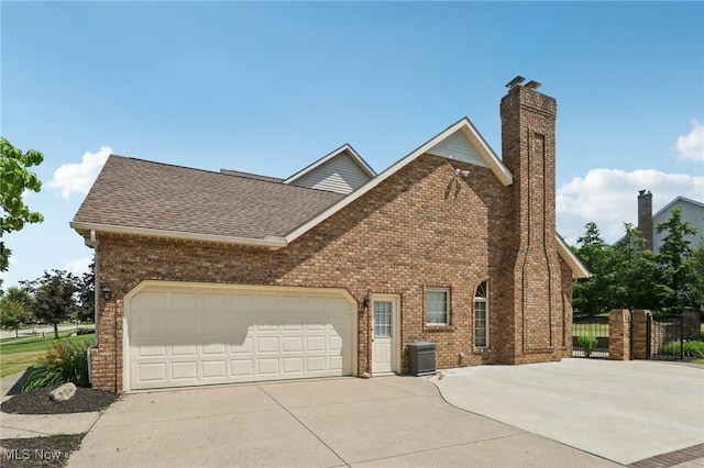 1101 Partridge Dr, Wadsworth, OH 44281 - view of home's exterior with concrete driveway, brick siding, a chimney, roof with shingles, and an attached garage