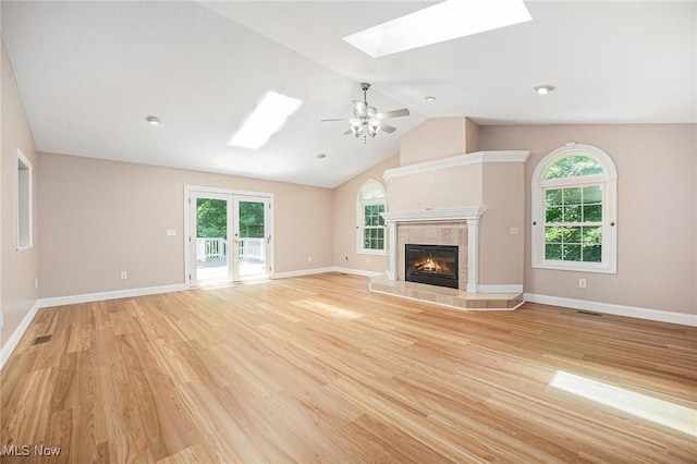 11801 Quail Crest Ave, Mantua, OH 44255 - unfurnished living room featuring a skylight, light wood finished floors, a tile fireplace, lofted ceiling, and ceiling fan