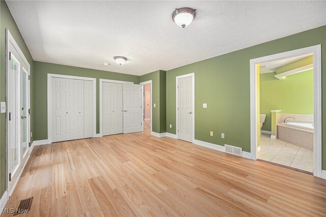 11801 Quail Crest Ave, Mantua, OH 44255 - unfurnished bedroom with light wood finished floors, two closets, and connected bathroom
