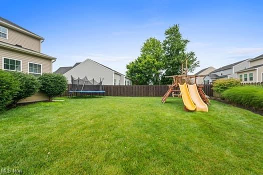 1932 Pinewood Ln, Painesville, OH 44077 - fenced backyard with a trampoline and a playground