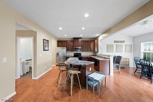 1932 Pinewood Ln, Painesville, OH 44077 - kitchen with stainless steel appliances, a kitchen bar, light wood finished floors, a kitchen island, and recessed lighting