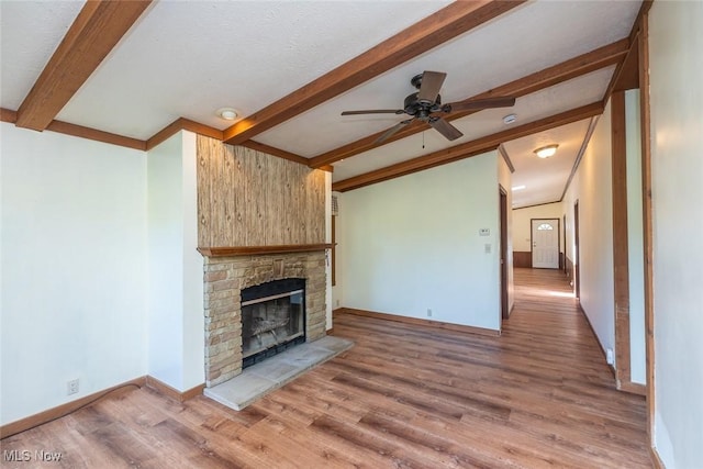 19 Pageant Ln, Olmsted Twp, OH 44138 - unfurnished living room with beamed ceiling, a ceiling fan, wood finished floors, and a stone fireplace
