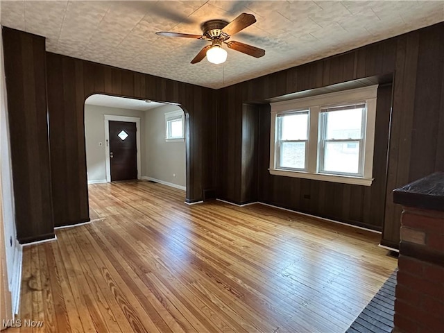 4011 E 29th St, Newburgh Heights, OH 44105 - spare room featuring arched walkways, a ceiling fan, wood walls, and light wood-type flooring