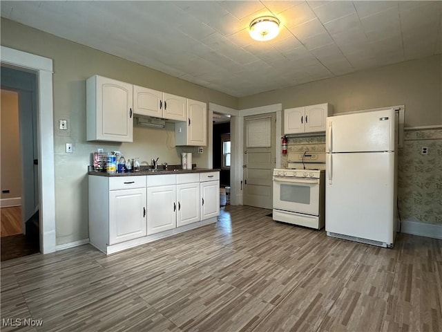 4011 E 29th St, Newburgh Heights, OH 44105 - kitchen featuring white appliances, dark countertops, light wood-style flooring, and white cabinets