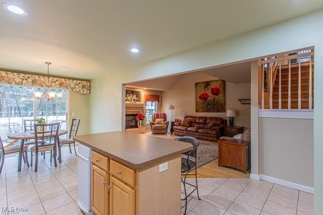 8121 Hitchcock Rd Unit 11, Boardman, OH 44512 - kitchen with light brown cabinets, light tile patterned floors, a breakfast bar area, a center island, and a fireplace