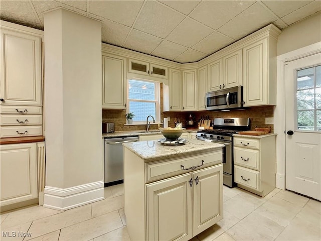 5519 4th Ave, Vienna, WV 26105 - kitchen with appliances with stainless steel finishes, tasteful backsplash, cream cabinetry, light tile patterned floors, and a kitchen island