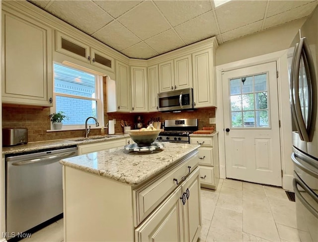 5519 4th Ave, Vienna, WV 26105 - kitchen with appliances with stainless steel finishes, tasteful backsplash, a kitchen island, light stone counters, and light tile patterned floors