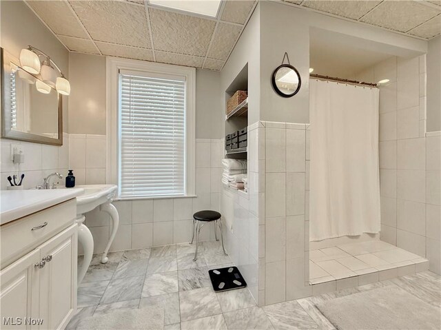 5519 4th Ave, Vienna, WV 26105 - full bath with tile walls, marble finish floors, a tile shower, vanity, and a wainscoted wall