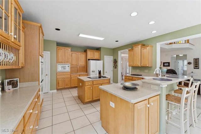 915 Cimarron Oval, Aurora, OH 44202 - kitchen with white appliances, a kitchen island, light countertops, a kitchen bar, and recessed lighting