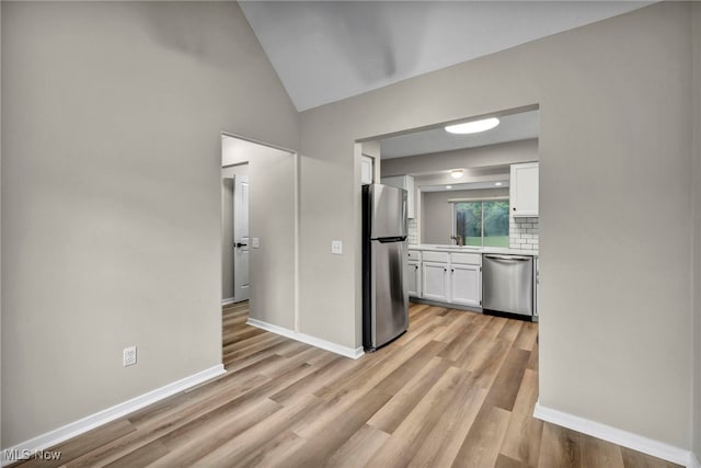 9543 Ridge Ct, Twinsburg, OH 44087 - kitchen with appliances with stainless steel finishes, white cabinetry, light countertops, lofted ceiling, and light wood-style flooring