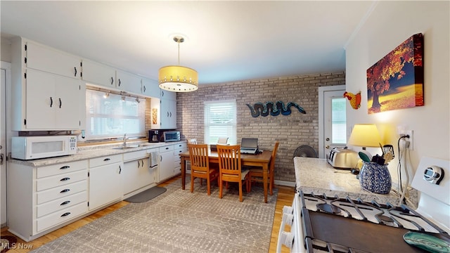500 Elm St, Belpre, OH 45714 - kitchen featuring white appliances, white cabinets, brick wall, light wood finished floors, and decorative light fixtures
