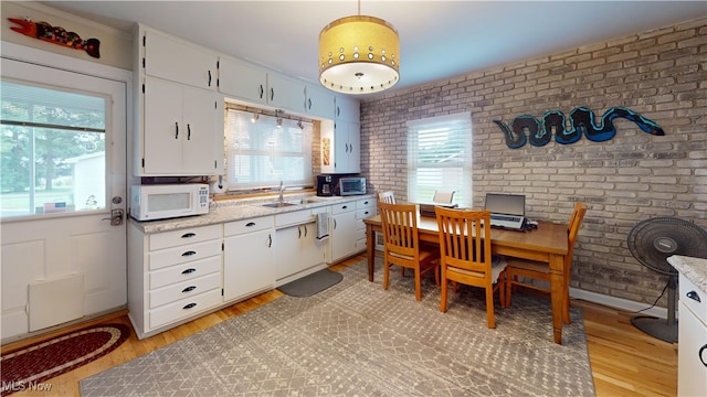 500 Elm St, Belpre, OH 45714 - kitchen with white microwave, plenty of natural light, brick wall, and light wood-type flooring