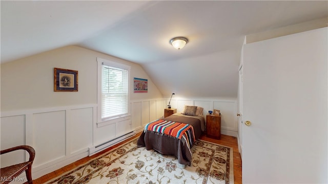 500 Elm St, Belpre, OH 45714 - bedroom with baseboard heating, light wood-style floors, wainscoting, lofted ceiling, and a decorative wall