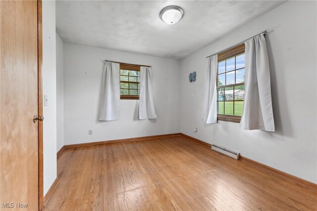 4130 Atwood Ave SE, Canton, OH 44707 - empty room with light wood finished floors, a baseboard heating unit, and healthy amount of natural light