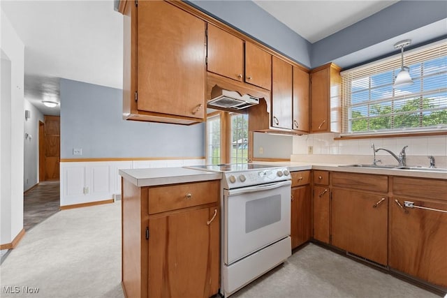 4130 Atwood Ave SE, Canton, OH 44707 - kitchen with white range with electric cooktop, brown cabinets, light countertops, under cabinet range hood, and wainscoting