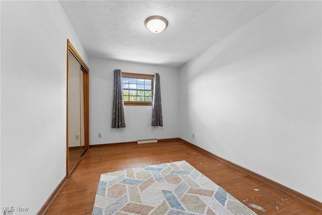 4130 Atwood Ave SE, Canton, OH 44707 - unfurnished bedroom with wood finished floors, a baseboard radiator, and a closet