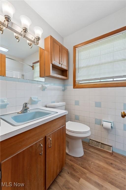 4130 Atwood Ave SE, Canton, OH 44707 - full bathroom with tile walls, vanity, a shower, and wood finished floors