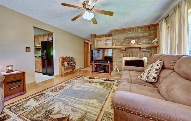 5882 Crooked Run Rd SW, New Philadelphia, OH 44663 - living room with ceiling fan, light wood-style floors, a textured ceiling, a fireplace, and healthy amount of natural light