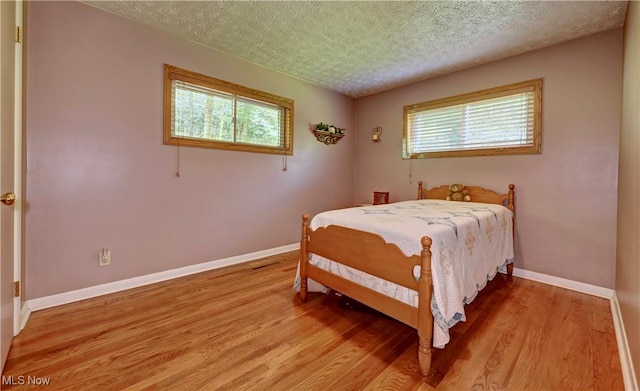 5882 Crooked Run Rd SW, New Philadelphia, OH 44663 - bedroom with multiple windows, a textured ceiling, and light wood-type flooring
