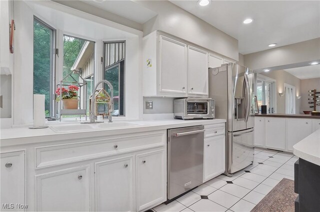 889 Eaton Ave, Akron, OH 44303 - kitchen with stainless steel appliances, white cabinets, light countertops, light tile patterned flooring, and recessed lighting
