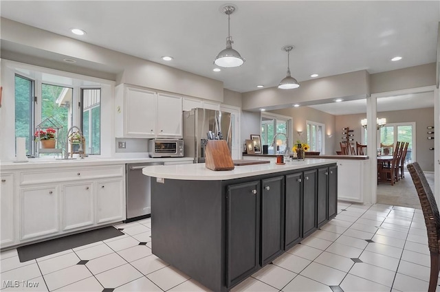 889 Eaton Ave, Akron, OH 44303 - kitchen featuring stainless steel appliances, white cabinetry, light countertops, pendant lighting, and a center island