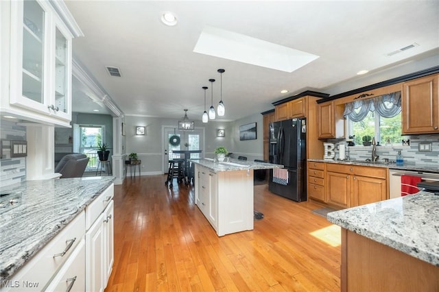 31 Anns Dr, Vienna, WV 26105 - kitchen featuring black fridge, a skylight, tasteful backsplash, light stone countertops, and plenty of natural light