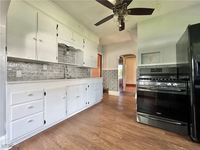 825 Summit St, Salem, OH 44460 - kitchen featuring stainless steel range with gas cooktop, arched walkways, light countertops, white cabinetry, and wood finished floors