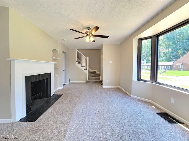 1006 Jackson Ave, Parkersburg, WV 26101 - unfurnished living room with a textured ceiling, carpet floors, stairway, a fireplace with flush hearth, and built in shelves