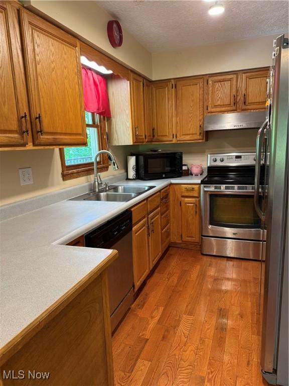 415 Middle Run Rd, Chester, WV 26034 - kitchen with appliances with stainless steel finishes, under cabinet range hood, light wood-type flooring, light countertops, and a textured ceiling