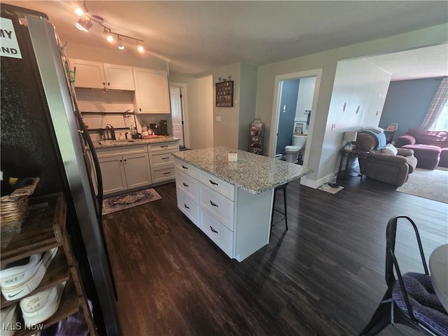 221 S Elm St, Jefferson, OH 44047 - kitchen with dark wood-style flooring, white cabinetry, a kitchen island, and a breakfast bar area