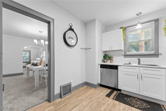 2602 Fletcher Ave NE, Canton, OH 44705 - kitchen with stainless steel dishwasher, white cabinets, light wood finished floors, backsplash, and light countertops