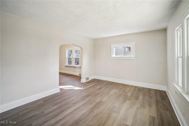 13713 Edgewood Ave, Cleveland, OH 44105 - spare room featuring arched walkways, wood finished floors, plenty of natural light, and a textured ceiling