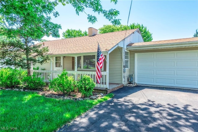 5149 Langfitt St, Vermilion, OH 44089 - single story home with asphalt driveway, a chimney, covered porch, an attached garage, and roof with shingles