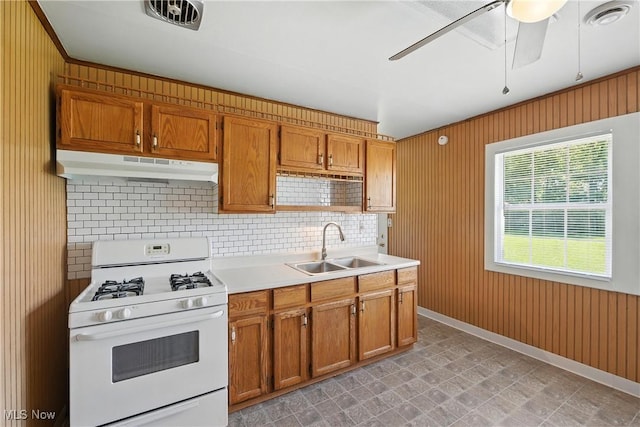 5149 Langfitt St, Vermilion, OH 44089 - kitchen with white gas stove, under cabinet range hood, ceiling fan, light countertops, and brown cabinetry