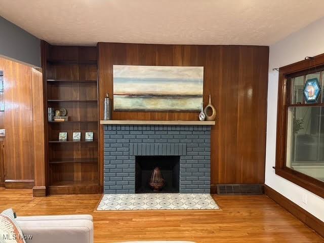 21430 Lakeshore Blvd, Euclid, OH 44123 - unfurnished living room featuring wood finished floors, a fireplace, and wood walls