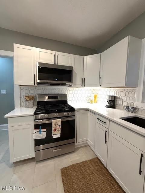 21430 Lakeshore Blvd, Euclid, OH 44123 - kitchen featuring stainless steel appliances, light countertops, light tile patterned flooring, and decorative backsplash