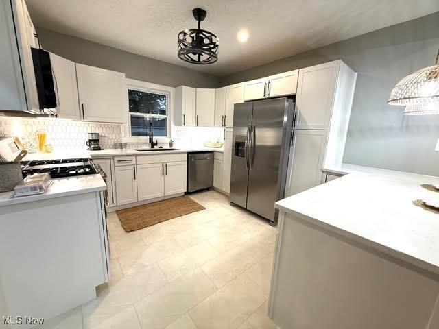 21430 Lakeshore Blvd, Euclid, OH 44123 - kitchen with appliances with stainless steel finishes, tasteful backsplash, light countertops, hanging light fixtures, and white cabinetry