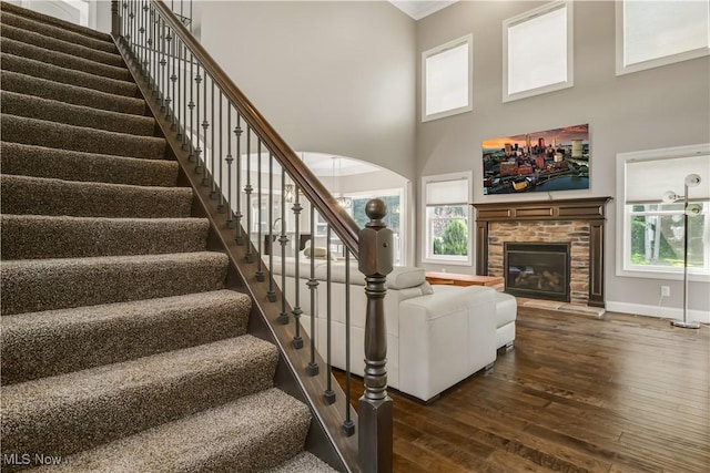 12110 Cora Ct, Concord, OH 44077 - stairway featuring hardwood / wood-style floors, a towering ceiling, a glass covered fireplace, arched walkways, and ornamental molding