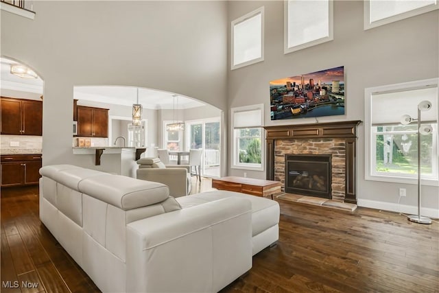 12110 Cora Ct, Concord, OH 44077 - living room with a high ceiling, dark wood-style floors, arched walkways, a stone fireplace, and a chandelier