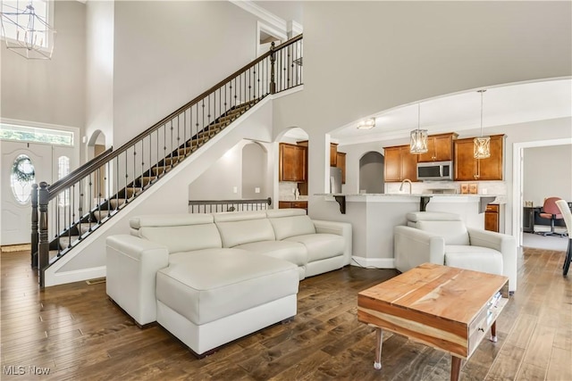 12110 Cora Ct, Concord, OH 44077 - living area featuring a towering ceiling, arched walkways, stairs, and dark wood-type flooring