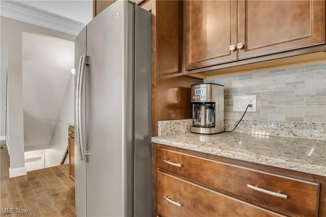 12110 Cora Ct, Concord, OH 44077 - kitchen featuring freestanding refrigerator, decorative backsplash, brown cabinets, light stone countertops, and ornamental molding