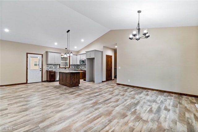 4720 Ashmont Ave SW, Canton, OH 44706 - kitchen with stainless steel microwave, a chandelier, light wood-type flooring, lofted ceiling, and decorative backsplash