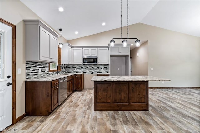 4720 Ashmont Ave SW, Canton, OH 44706 - kitchen featuring appliances with stainless steel finishes, lofted ceiling, light wood-style floors, a kitchen island, and backsplash