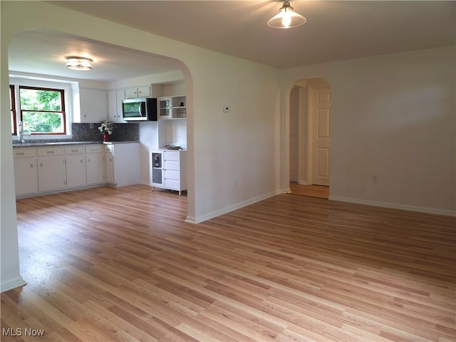 4581 Smith Stewart Rd, Vienna, OH 44473 - kitchen featuring stainless steel microwave, arched walkways, light wood-type flooring, and white cabinets