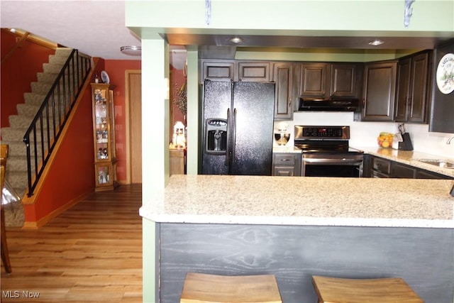 3545 Malley Ave, Coventry Township, OH 44319 - kitchen with stainless steel range with electric cooktop, black fridge with ice dispenser, under cabinet range hood, light wood finished floors, and dark brown cabinetry